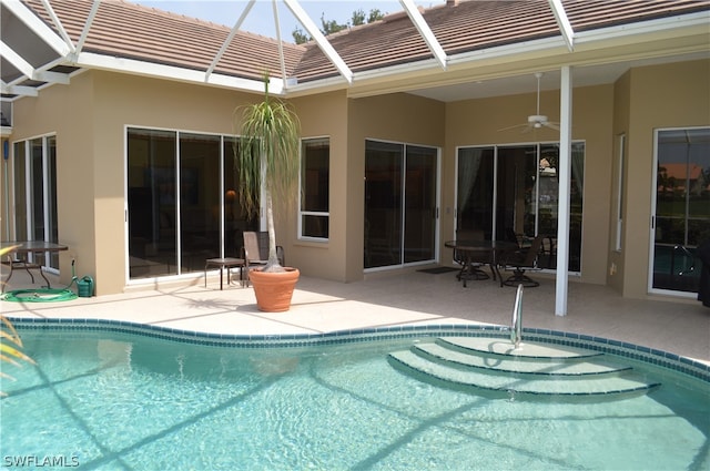 view of swimming pool with ceiling fan, glass enclosure, and a patio