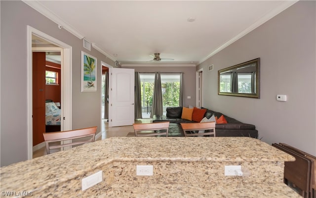 kitchen featuring tile floors, ceiling fan, ornamental molding, and light stone countertops