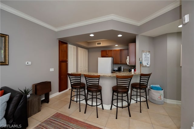 kitchen featuring white fridge, kitchen peninsula, light stone countertops, ornamental molding, and light tile floors