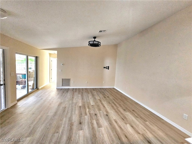 spare room with light hardwood / wood-style floors and a textured ceiling