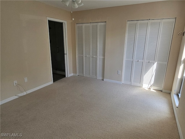 unfurnished bedroom featuring carpet floors and multiple closets