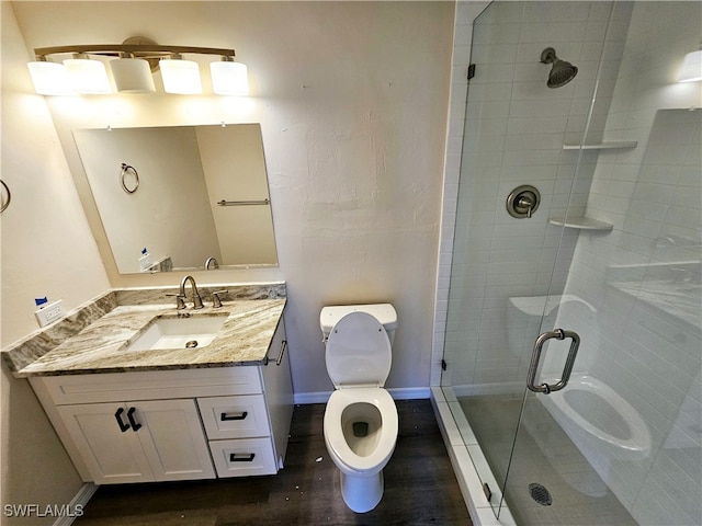 bathroom with vanity, toilet, hardwood / wood-style flooring, and a shower with shower door