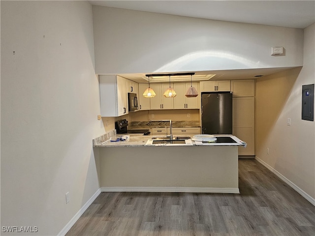 kitchen with kitchen peninsula, hardwood / wood-style floors, black appliances, pendant lighting, and sink