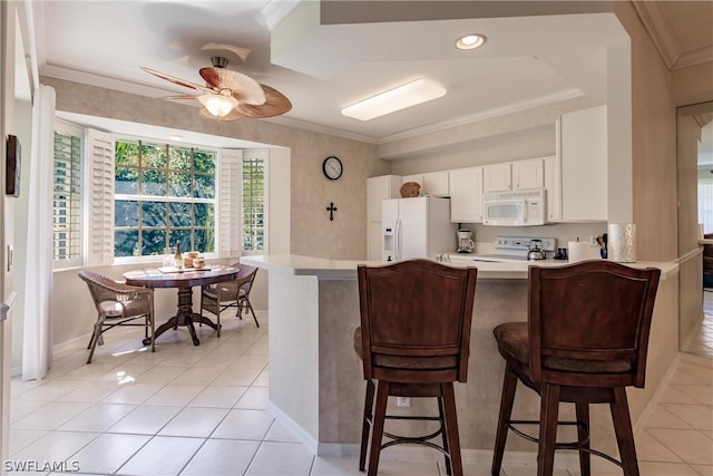 kitchen featuring light tile flooring, ceiling fan, a kitchen bar, white cabinetry, and white appliances