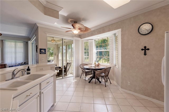 kitchen featuring ceiling fan, light tile floors, ornamental molding, white cabinets, and sink