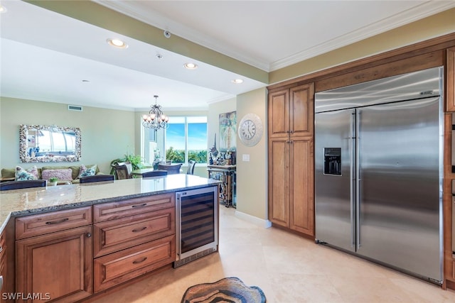 kitchen featuring light stone counters, stainless steel built in fridge, pendant lighting, beverage cooler, and an inviting chandelier