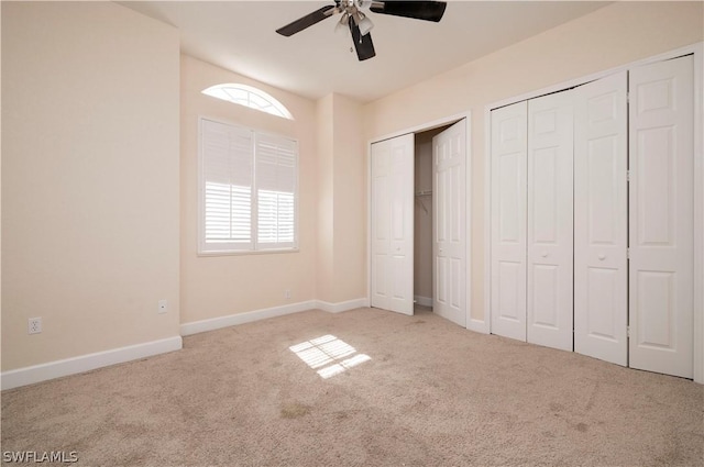 unfurnished bedroom with multiple closets, multiple windows, ceiling fan, and light carpet