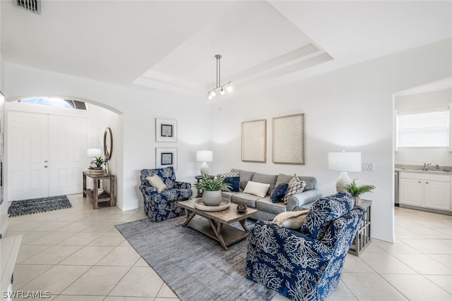 living room featuring light tile patterned flooring and a tray ceiling