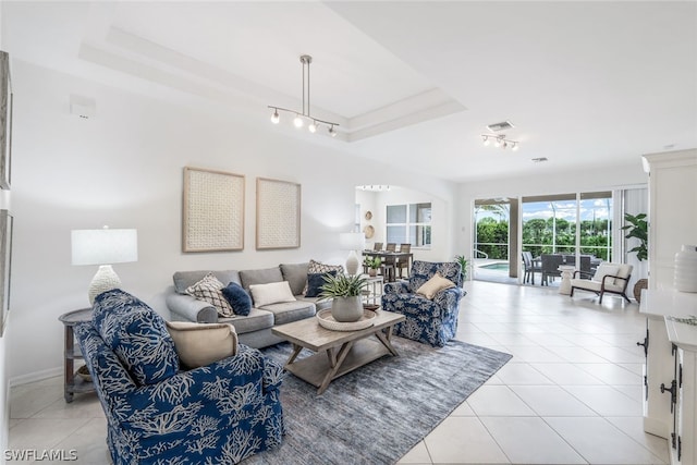 living room with a raised ceiling and light tile patterned flooring