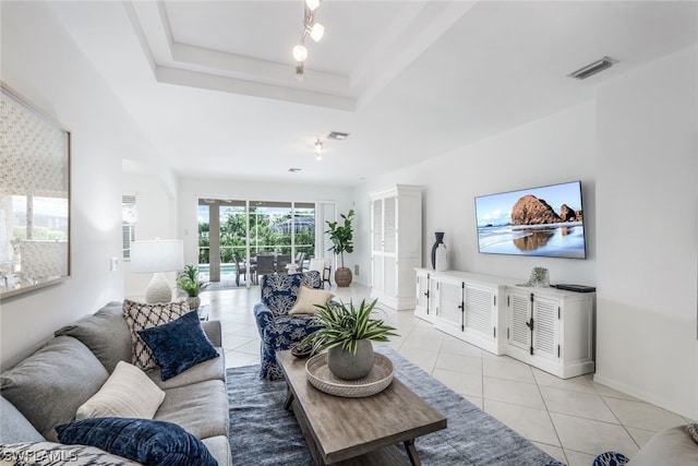 living room with a raised ceiling and light tile patterned floors