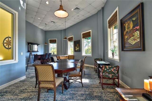 carpeted dining room with a high ceiling and a paneled ceiling