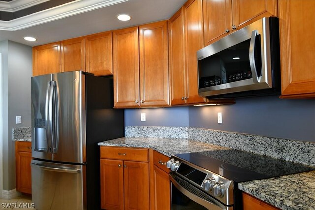 kitchen featuring light stone counters, crown molding, and stainless steel appliances