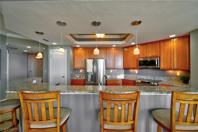 kitchen featuring hanging light fixtures, a raised ceiling, crown molding, a center island with sink, and appliances with stainless steel finishes