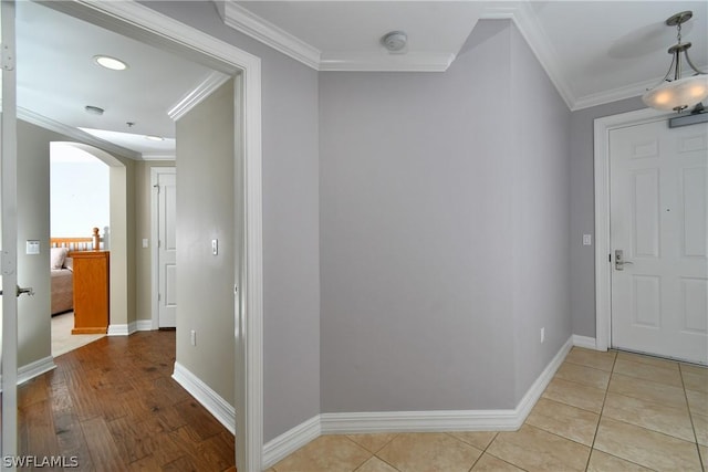 hallway with baseboards, arched walkways, and ornamental molding