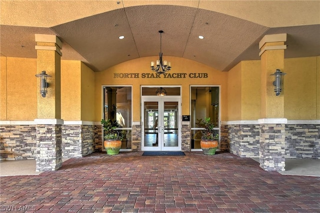 view of exterior entry with french doors, stone siding, and stucco siding