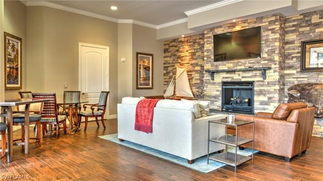 living room featuring a stone fireplace, ornamental molding, and dark wood-type flooring