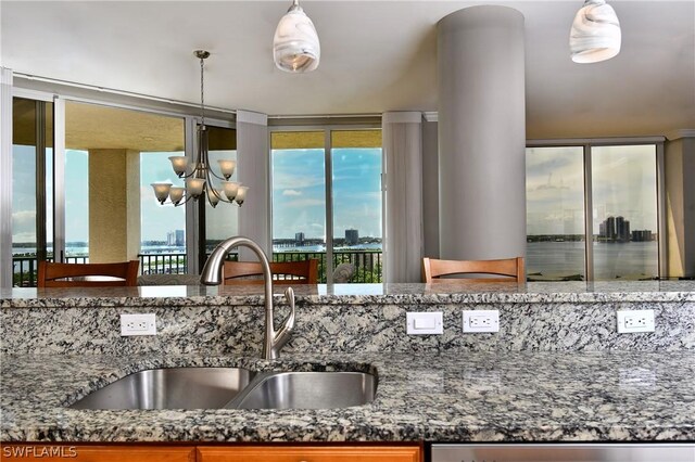 kitchen featuring stone counters, a wealth of natural light, sink, and a notable chandelier