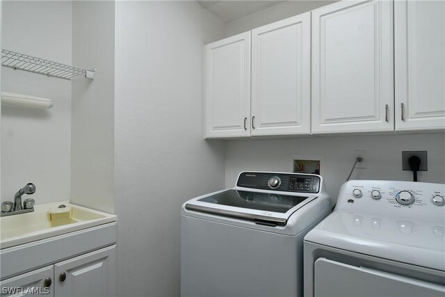 laundry room with washing machine and dryer, sink, and cabinets