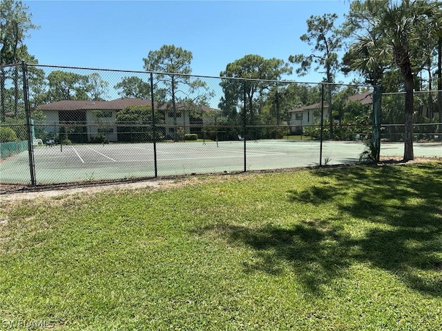 view of tennis court with a yard