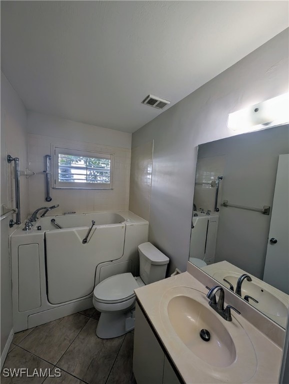 bathroom featuring tile patterned flooring, vanity, toilet, and a washtub