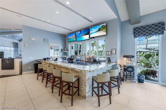 bar with a high ceiling, light tile patterned flooring, and light stone counters