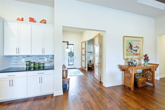 kitchen with backsplash, white cabinets, and dark wood-type flooring