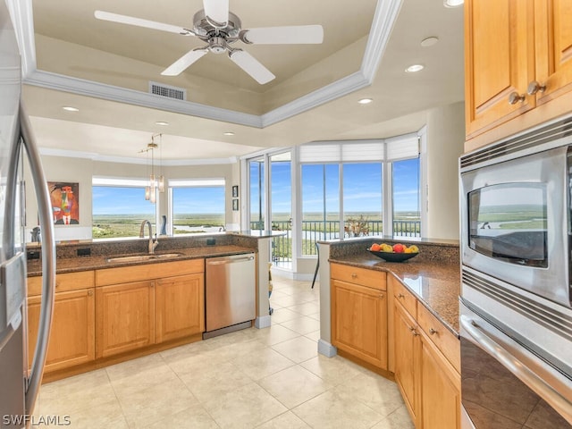 kitchen featuring dark stone counters, crown molding, sink, hanging light fixtures, and stainless steel appliances