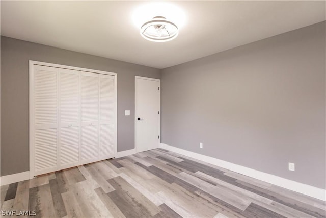 unfurnished bedroom with light wood-type flooring and a closet