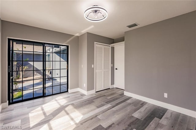 empty room with light hardwood / wood-style floors and plenty of natural light