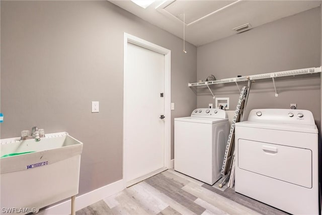 laundry room featuring sink, light hardwood / wood-style flooring, and independent washer and dryer