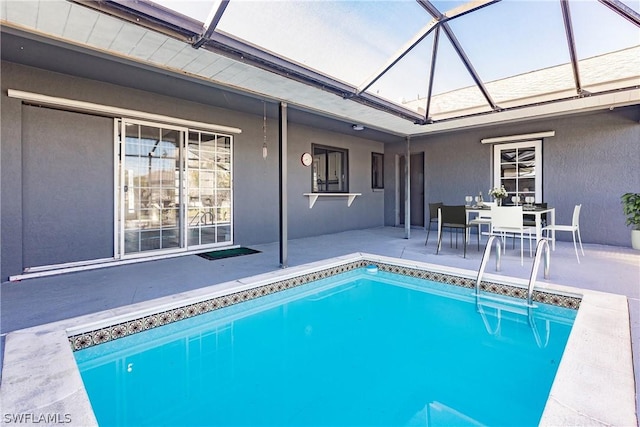 view of pool with glass enclosure and a patio