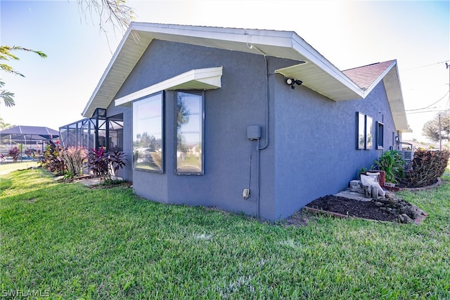 view of side of property with a lanai and a yard