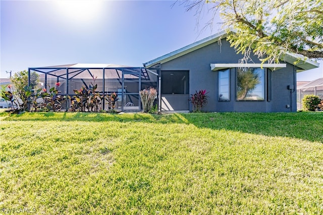 rear view of house with a lawn and glass enclosure