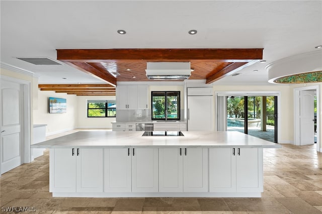 kitchen featuring a large island with sink, white cabinets, beamed ceiling, and a healthy amount of sunlight