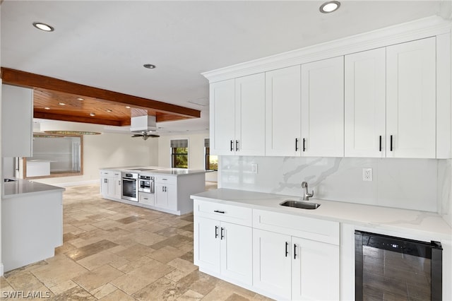 kitchen with white cabinetry, sink, beverage cooler, beamed ceiling, and oven