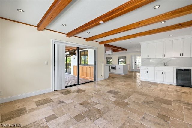 unfurnished living room with plenty of natural light, beamed ceiling, and beverage cooler