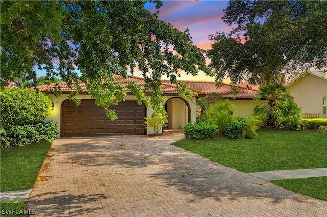 mediterranean / spanish house with a lawn and a garage