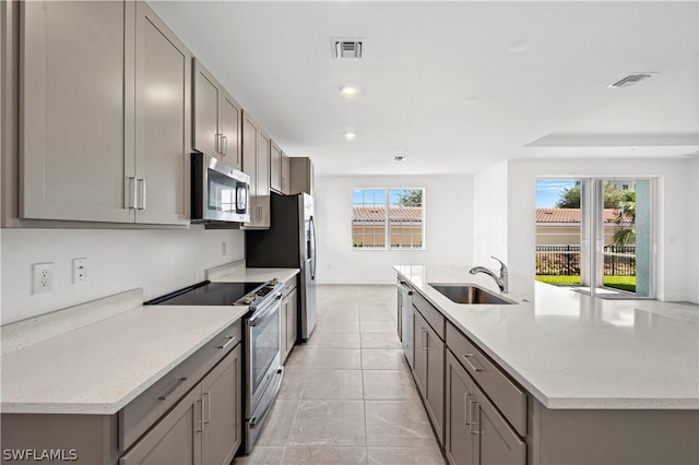 kitchen featuring light tile patterned flooring, stainless steel appliances, gray cabinetry, and sink