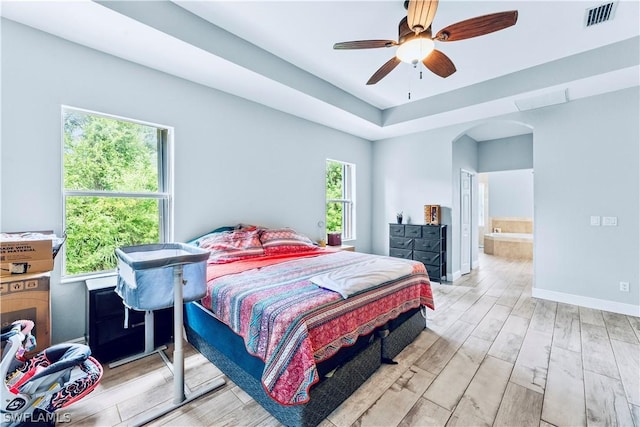 bedroom featuring light wood-type flooring, ceiling fan, and connected bathroom