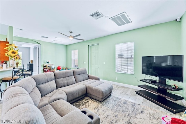 living room featuring a wealth of natural light, light hardwood / wood-style flooring, and ceiling fan