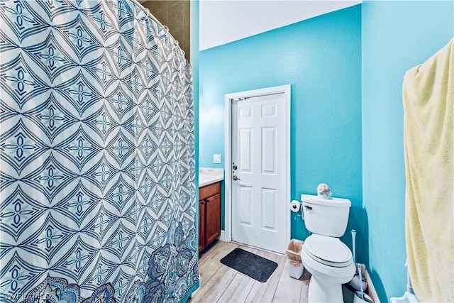 bathroom with hardwood / wood-style floors, vanity, toilet, and walk in shower