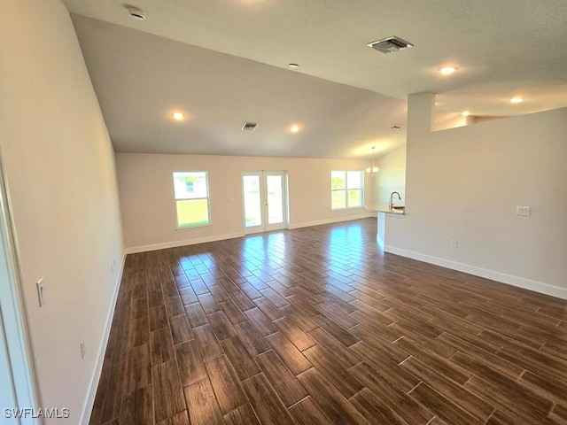 unfurnished room with lofted ceiling, a notable chandelier, and dark hardwood / wood-style flooring