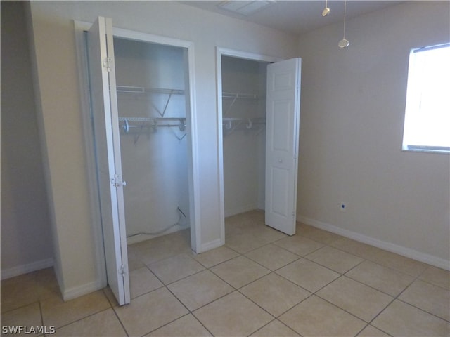 unfurnished bedroom with multiple closets and light tile floors