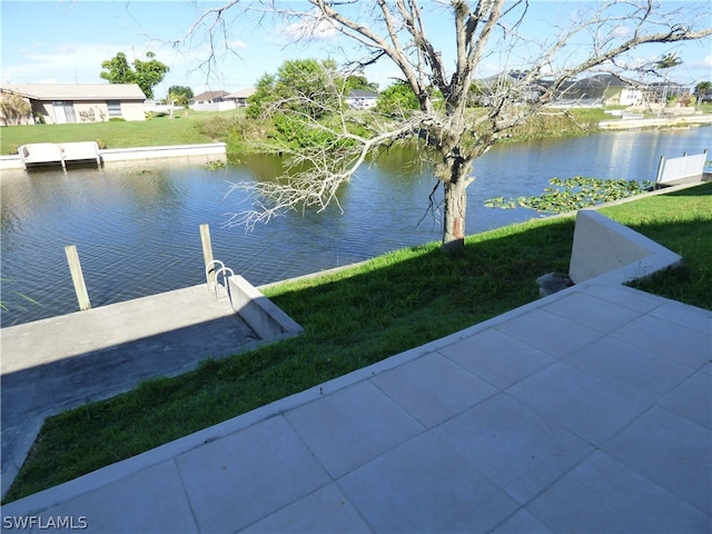 view of dock with a lawn and a water view