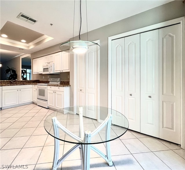 kitchen with white appliances, hanging light fixtures, white cabinetry, and a raised ceiling