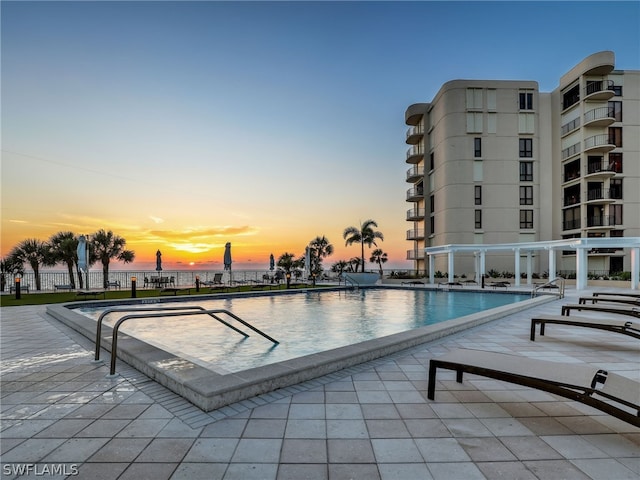 pool at dusk with a patio area