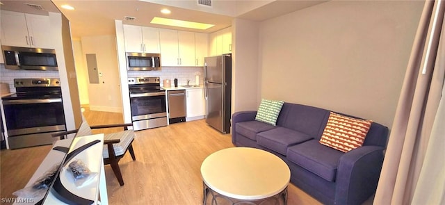 kitchen featuring white cabinets, appliances with stainless steel finishes, backsplash, and light hardwood / wood-style flooring