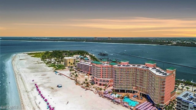 aerial view at dusk with a view of the beach and a water view