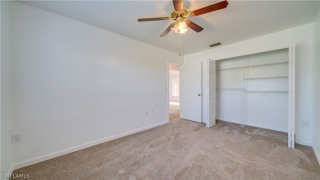 unfurnished bedroom with light carpet, a closet, and ceiling fan