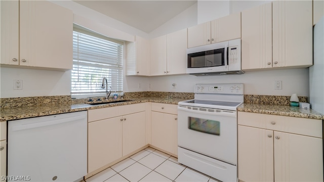 kitchen with white appliances, light stone counters, light tile floors, sink, and lofted ceiling